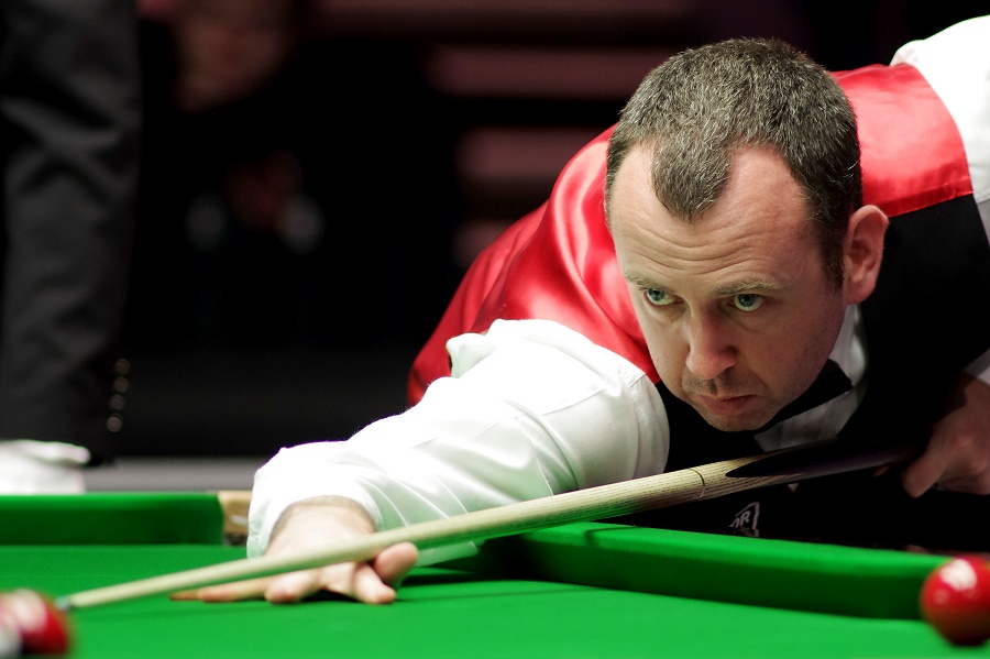 Mark Williams leans in to play a shot against Judd Trump
