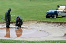 The greens staff pump water out of a bunker next to the 18th green