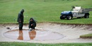 Greens staff pump water out of a bunker on the 18th hole