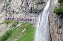 The peloton passes under a waterfall