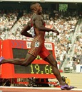 Michael Johnson runs past the clock after crossing the finish line